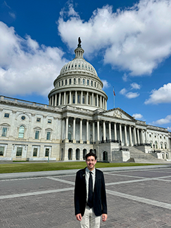 Cristian standing outside with the Capitol Building behind him